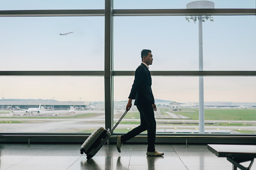 side view of asian businessman with business suit walking in airport terminal before boarding