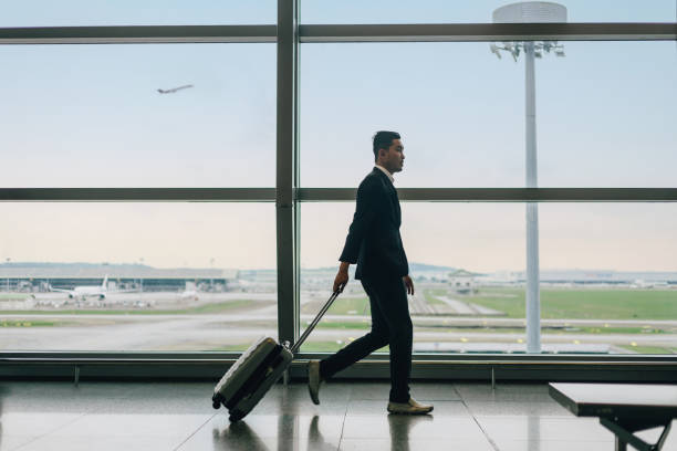 Businessman with suitcase walking in airport stock photo