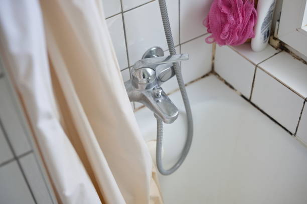 Old dirty bathtub, shower curtain, and faucet in an apartment bathroom. Top view, white faience wall, no people stock photo