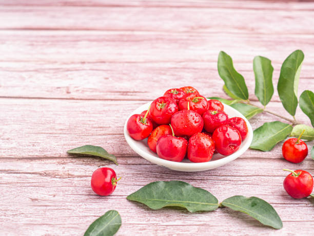 istock Ripe red cherries in a ceramic dish with leaves on wooden table 1410991232