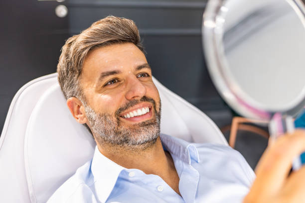 Middle aged man reviewing wrinkles in hand mirror. stock photo