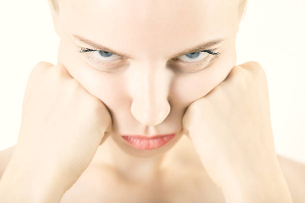 Sadness, sorrow in a Hispanic young woman about to cry. Hispanic young woman with grief  expression and hands on head. Head and shoulders close up shot with model looking to camera. Image Isolated on white background with clipping path. Studio shot of face expressions female series,  Predominant color: white. High key DSLR studio photo taken with a Canon 5D Mk III and a class L Pro lens for maximum sharpness.