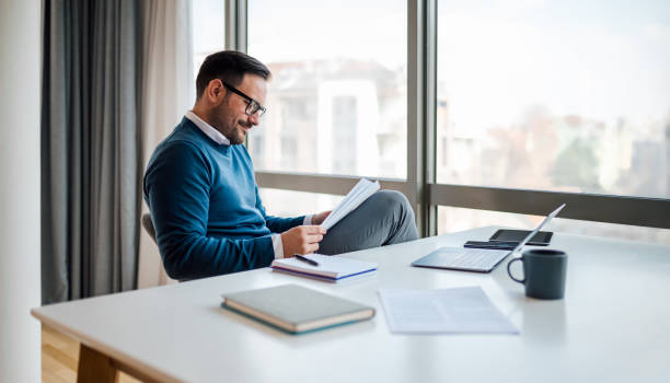 istock Confident male professional analyzing documents while sitting at desk in the office. 1410991534