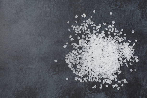 istock Sea salt in wooden bowl on black table. 1410991926