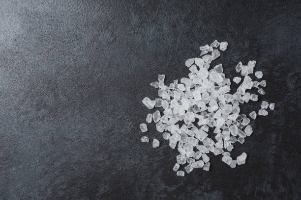 istock Sea salt in wooden bowl on black table. 1410991928