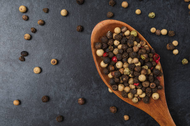 istock Pepper in wooden bowl on dark black stone table with copy space. 1410992104