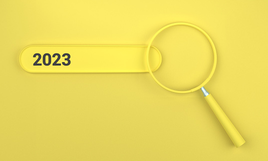 Searching for 2023 in search bar with magnifying glass. SEO concept on yellow background.