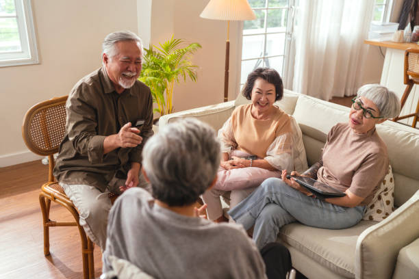old senior asian friends retired people hapiness positive laugh smile conversation together at living room at nursing home Seniors participating in Group Activities in Adult Daycare Center stock photo