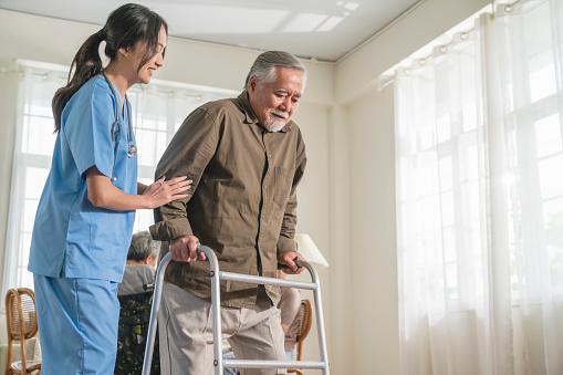 young asian female nurse care giver helping asian senior old man with mobility walker in living area of nursing home senior daycare center,Nurse take care elderly patient with cheerful concentrate