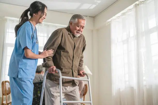Photo of young asian female nurse care giver helping asian senior old man with mobility walker in living area of nursing home senior daycare center,Nurse take care elderly patient with cheerful concentrate