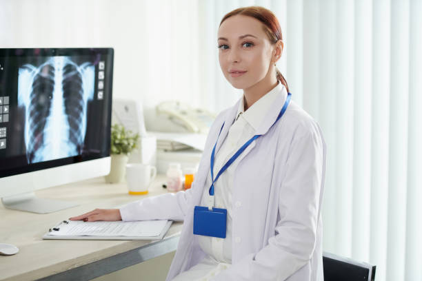 Pulmonologist Checking X-ray Portrait of young female pulmonologist checking x-ray of recovering patient and filling document x ray results stock pictures, royalty-free photos & images