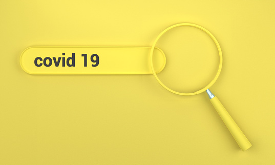 Searching for Covid 19 in search bar with magnifying glass. SEO concept on yellow background.