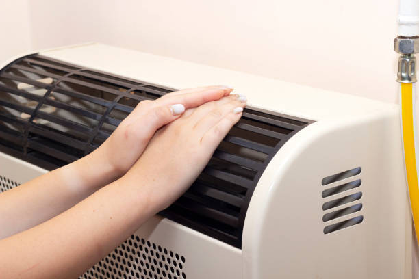 istock hard hands on the heating radiator, warm hands 1410996643