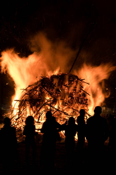 Silhouette of people watching a bonfire burn