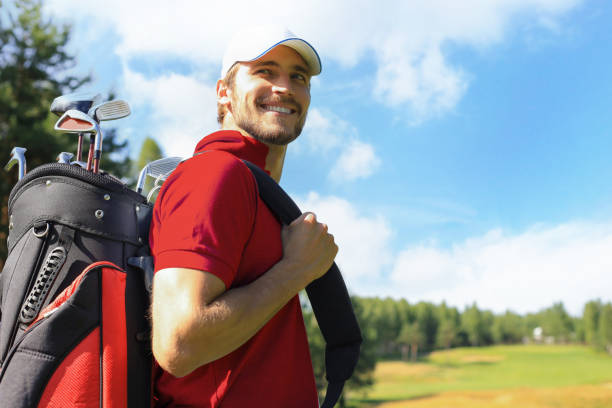 Golf player walking and carrying bag on course during summer game golfing