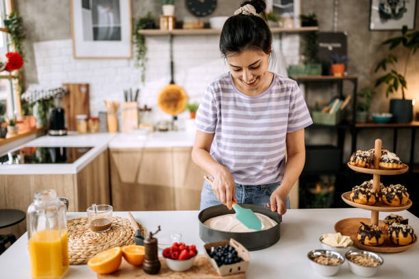 istock Woman spreading cheesecake mixture on baking tin 1410998358