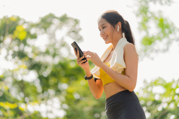sport active asian female sport cloth setting up smartphone playing prepare for her running routine workout morning healthy lifestyle,smiling sport woman setting runing route in her application map sport active asian female sport cloth setting up smartphone playing prepare for her running routine workout morning healthy lifestyle,smiling sport woman setting runing route in her application map exercise stock pictures, royalty-free photos & images