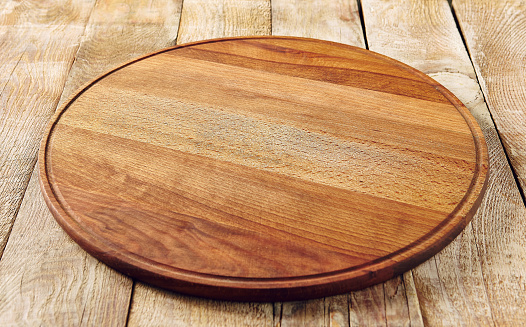 Cutting board on wooden surface. Cooking process, rustic style