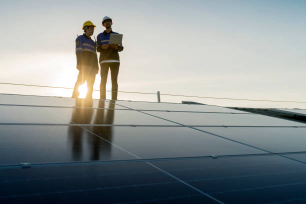 istock Specialist technician professional engineer with laptop and tablet maintenance checking installing solar roof panel on the factory rooftop under sunlight. Engineers team survey check solar panel roof. 1411000949