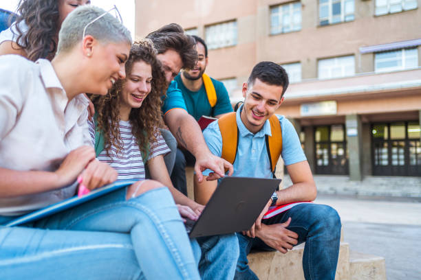 istock Group of students gathers around a laptop 1411001392