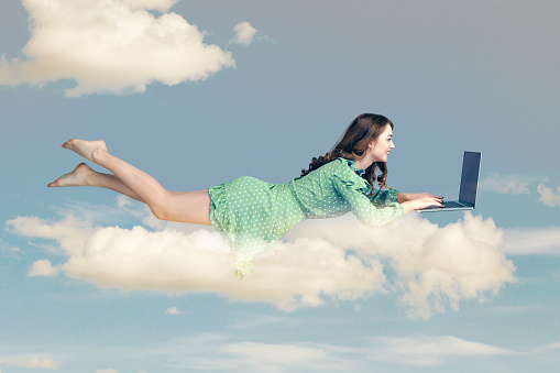 Hovering in air. Happy cheerful girl ruffle dress levitating with laptop, typing keyboard, reading good news message on computer while flying in mid-air. collage composition on day cloudy blue sky