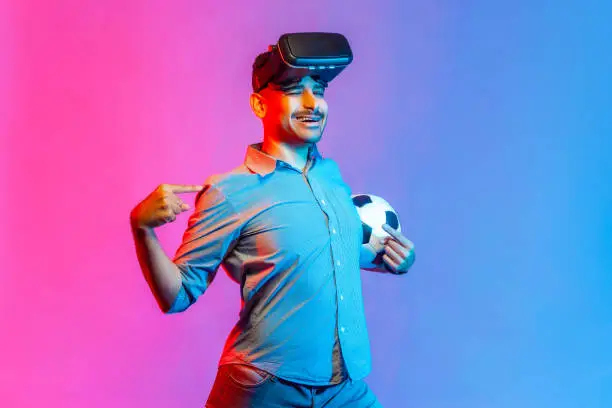 Photo of Man in virtual reality glasses, standing with satisfied expression, pointing at himself with proud.