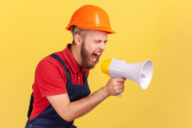 istock Worker wearing protective helmet holding megaphone and screaming with aggressive expression. 1411001814