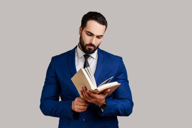 istock Concentrated bearded man reading book, enjoying reading, standing absorbed with exciting plot. 1411001868