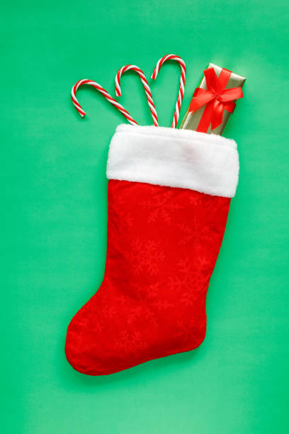 istock Christmas stocking with gift box and candy canes on green background. 1411002223