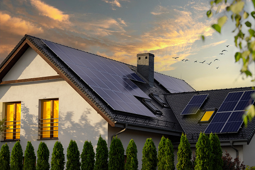 istock Solar photovoltaic panels on a house roof. Sunset. 1411002313