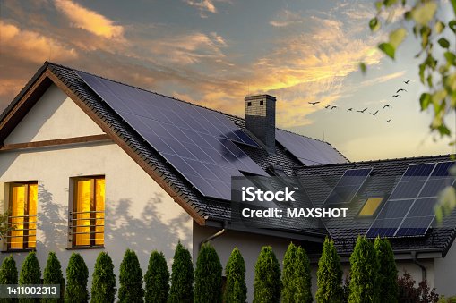 istock Solar photovoltaic panels on a house roof. Sunset. 1411002313