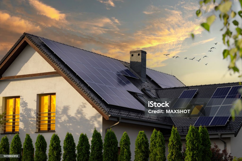 Solar photovoltaic panels on a house roof. Sunset. Modern house with solar panels. Night view of a beautiful white house with solar panels. Solar Panel Stock Photo