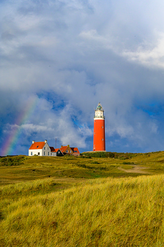 Lighthouse at the Wadden island Texel in the dunes with a rainbow during a stormy autumn morning. The Eierland lighthouse is located at the North point of the island.