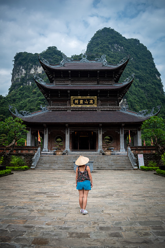 Young tourist in Vietnam. Tourist touring Vietnamese temples. Vietnam temple, lost among beautiful mountains. Tam Coc caves and temples. Tourist in Tam Coc, Vietnam