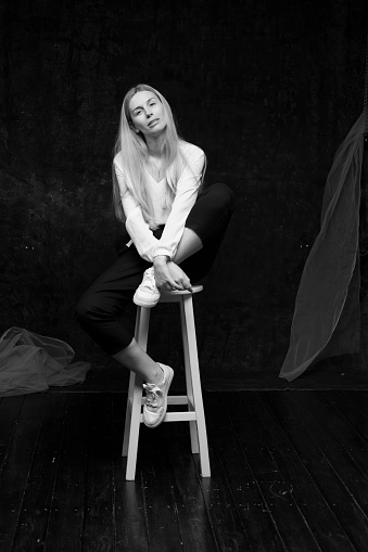 portrait of a girl on a dark gray background.a young beautiful Ukrainian girl posing on a dark gray background with different emotions. blonde with long hair in a white blouse and black trousers isolated.