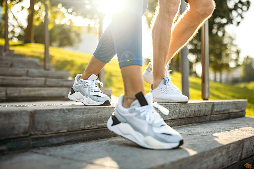 Unrecognisable friends running on a stairs in public park