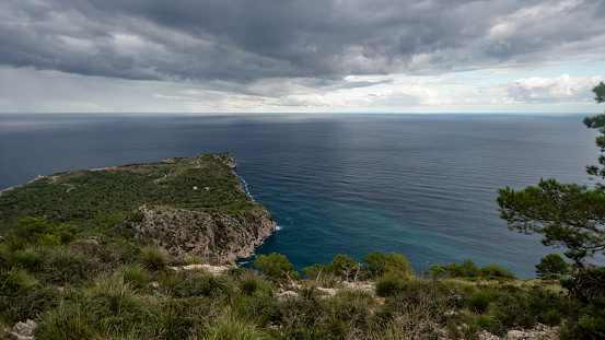 Scenic view of Mediterranean sea, Alcudia in Balearic Islands. Spain, Spanish landscape. Beautiful nature and mountain rock. Storm clouds on the sky. Forest and sand around