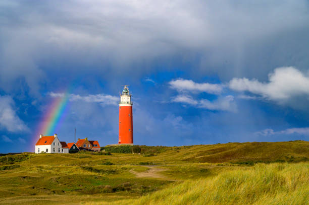 Lighthouse at the Wadden island Texel in the dunes with a rainbow during a stormy autumn morning. The Eierland lighthouse is located at the North point of the island.