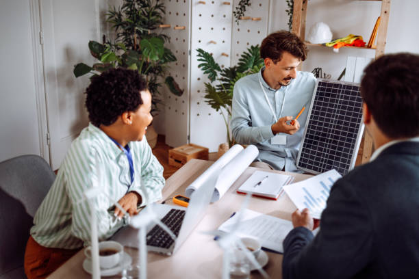 istock Young man holding a presentation of his solar panel model to his colleagues in the office 1411005253