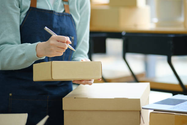 istock Online small business owner writing address on parcel box. 1411005752