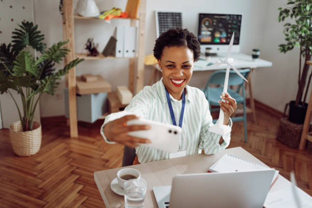 istock Female eco engineer taking a selfie with windmill model in her hands 1411005781