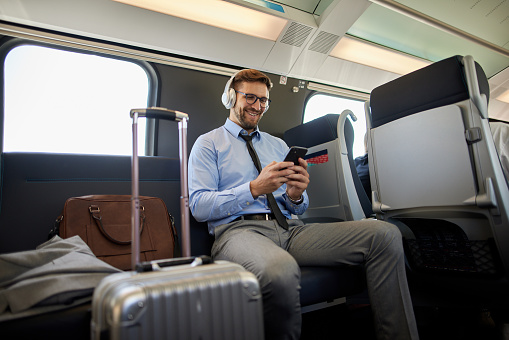 Businessman using phone and making video call while traveling by the train