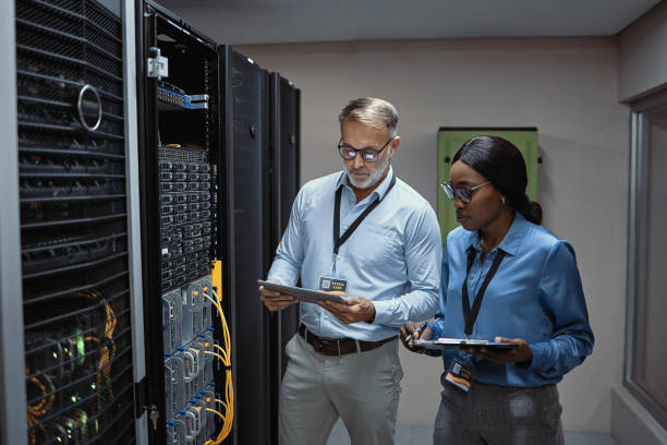 istock IT technicians holding clipboards in a server room preparing to repair hardware. Male and female computer engineers consulting on upgrading software for online security in a data information center 1411009459