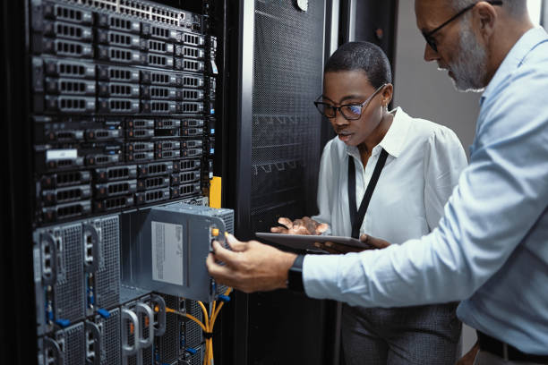 istock Male computer engineer and female network analyst looking at hard drives, diagnosing and assessing network problems and issues for connectivity. Two IT professionals working in a server room. 1411009516