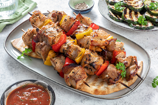 Delicious kebabs with vegetables and pita bread on a wooden table
