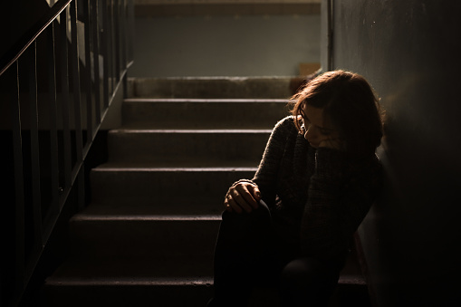 woman in a dark sweater at the steps, concept of loneliness and depression, selective focus, dark style, abstraction