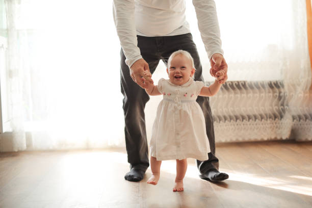 istock little daughter first steps with her father 1411011522