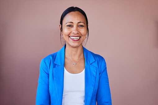 Portrait of a mature businesswoman laughing while standing in front of a wall in an office