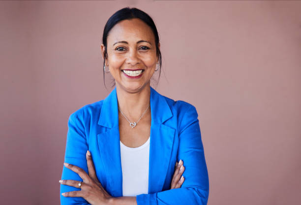 Smiling mature businesswoman standing with her arms crossed at work stock photo