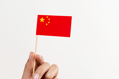 Hand is holding Chinese flag on pure white background.